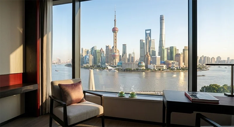 A panoramic view from a luxury hotel window in Shanghai overlooking the Lujiazui financial district and the Pearl Tower.