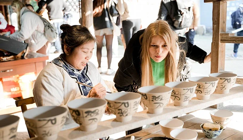 Tourists observe handmade porcelain-making techniques at an ancient kiln