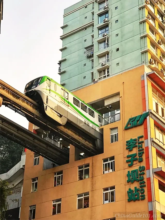 Chongqing's famous Liziba Station where a green and white Line 2 monorail train is seen passing directly through a hole in a 19-story residential apartment building.