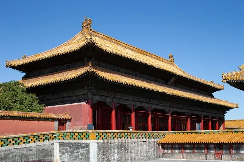 A side-angle view of the Palace of Earthly Tranquility at the Palace Museum, Beijing, highlighting the traditional double-eaved golden roof and red imperial facade against a solid blue sky