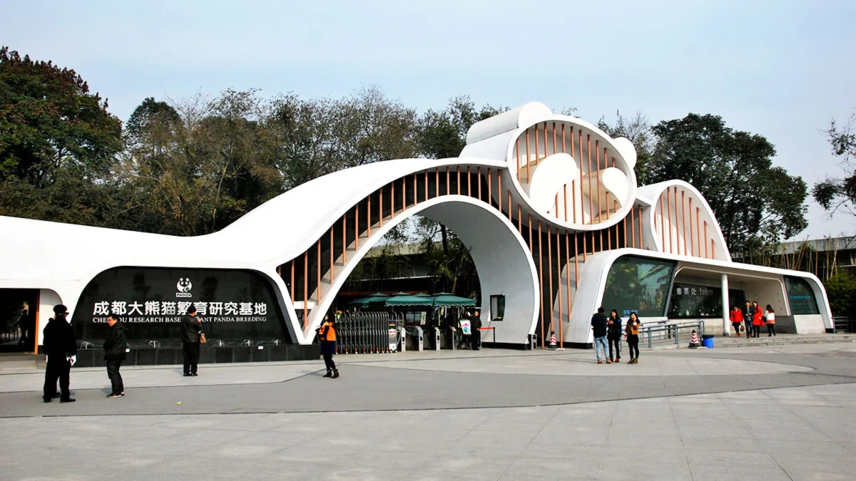 Modern panda-shaped main entrance gate of the Chengdu Research Base of Giant Panda Breeding with visitors walking in front.