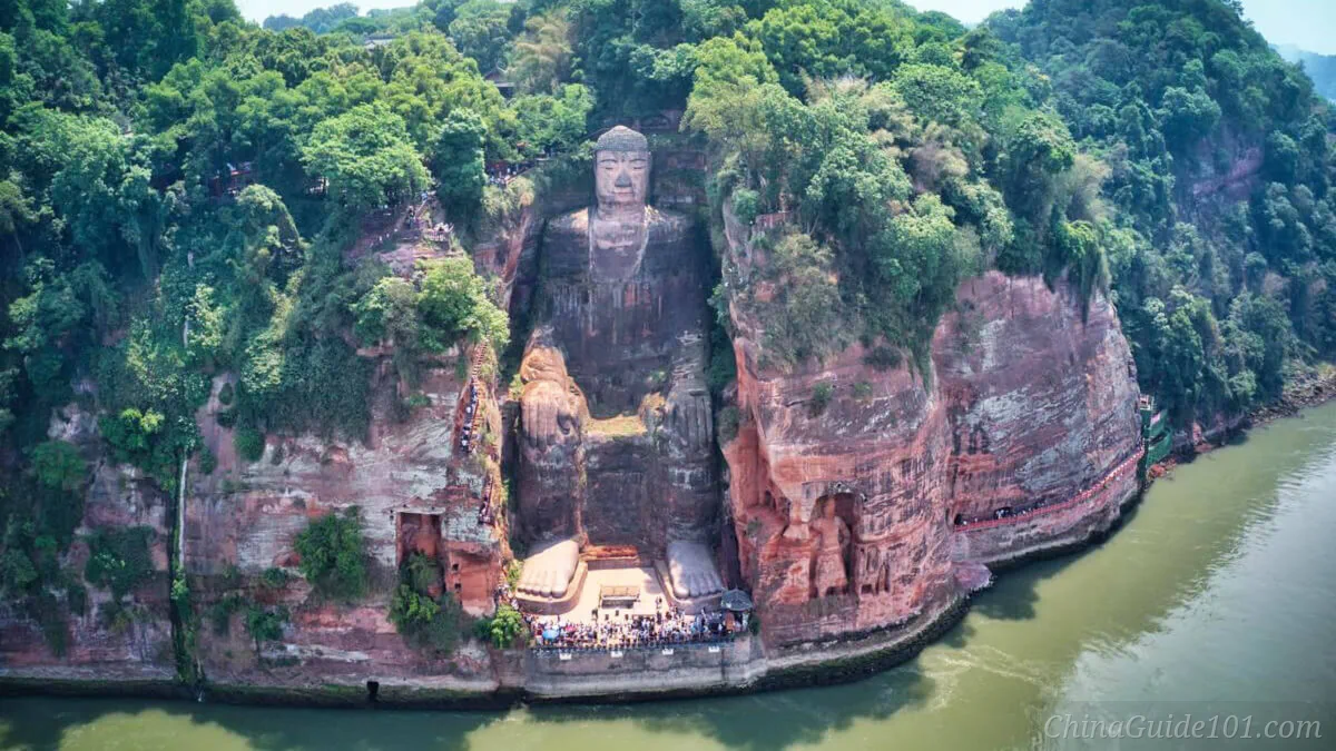 Aerial full view of the Leshan Giant Buddha carved into the red sandstone cliff facing the river in Sichuan, China