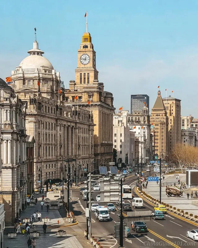 Daytime street view of historic architecture on The Bund in Shanghai, featuring the iconic Customs House clock tower and street traffic