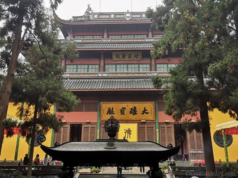 The exterior view of the Grand Hall of the Great Hero (Mahavira Hall) at Lingyin Temple in Hangzhou, featuring multi-tiered traditional Chinese roofs, a large golden plaque, and a bronze incense burner in the foreground.