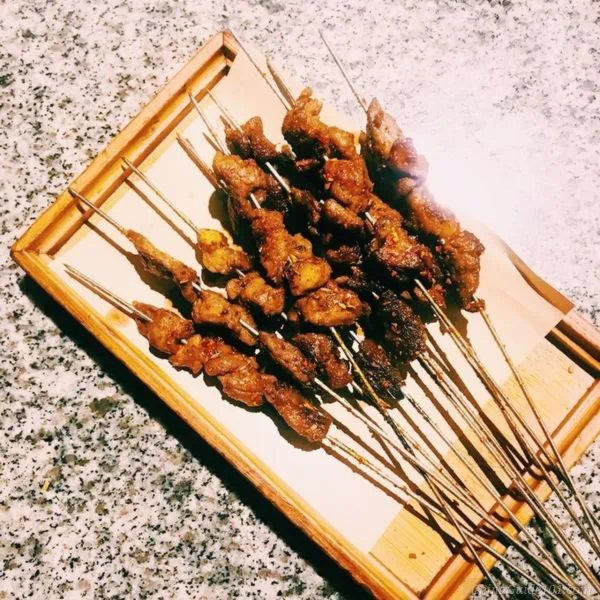 grilled lamb skewers from xi'an muslim street, spiced roasted mutton meat skewers on wooden tray, classic shaanxi street barbecue