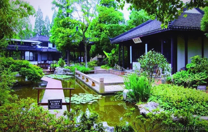 Kezhi Garden in Zhujiajiao Water Town, Shanghai. Classical Chinese garden scene with a pond, lily pads, wooden walkway, traditional pavilions and lush green trees