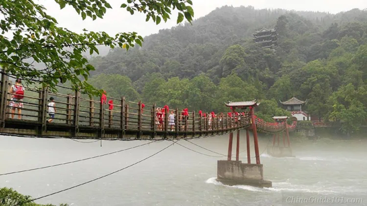 Anlan Suspension Bridge at Dujiangyan Irrigation System. Visitors walk across the historic wooden cable bridge over the rushing Min River