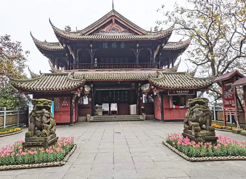 Qinyan Tower at Dujiangyan Irrigation System, Sichuan. Traditional multi-story Chinese wooden pavilion with upturned eaves, guarded by two ancient stone lions at the entrance