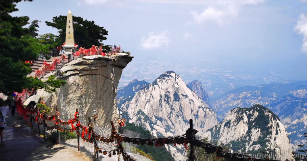 Scenic overlook at Huashan East Peak, with obelisk, red wish ribbons and steep granite mountain summits