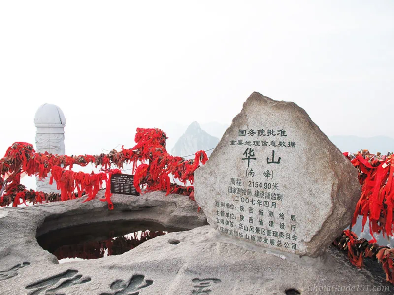 Official elevation stone marker of Huashan South Peak (Luoyan Peak), covered with red prayer ribbons and love locks
