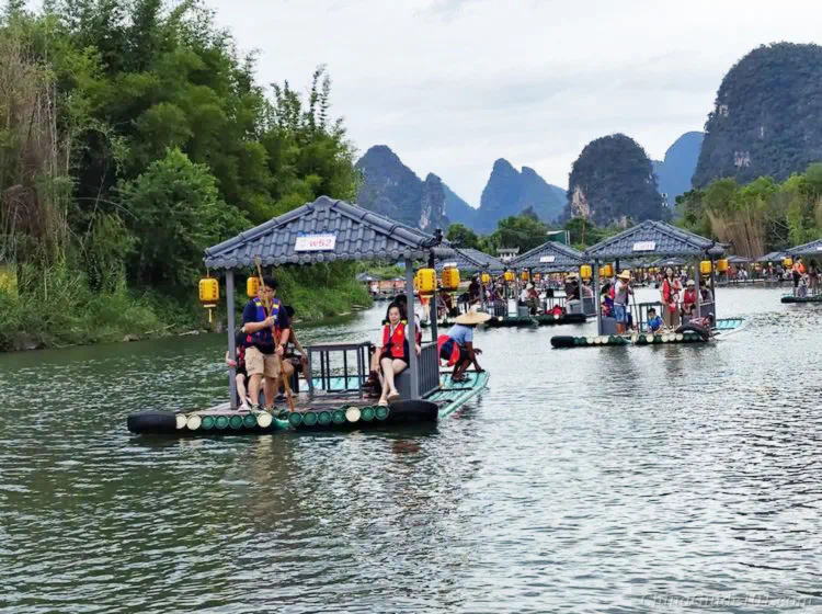 Covered tourist bamboo rafts for 4 or 8 passengers on Yulong River, Yangshuo, with karst peaks in background